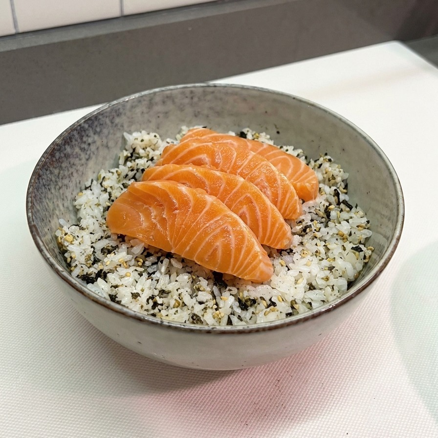 Quatre tranches de saumon dun orange vif disposées soigneusement sur un lit de riz blanc parsemé de paillettes dalgues noires dans un bol en céramique gris.