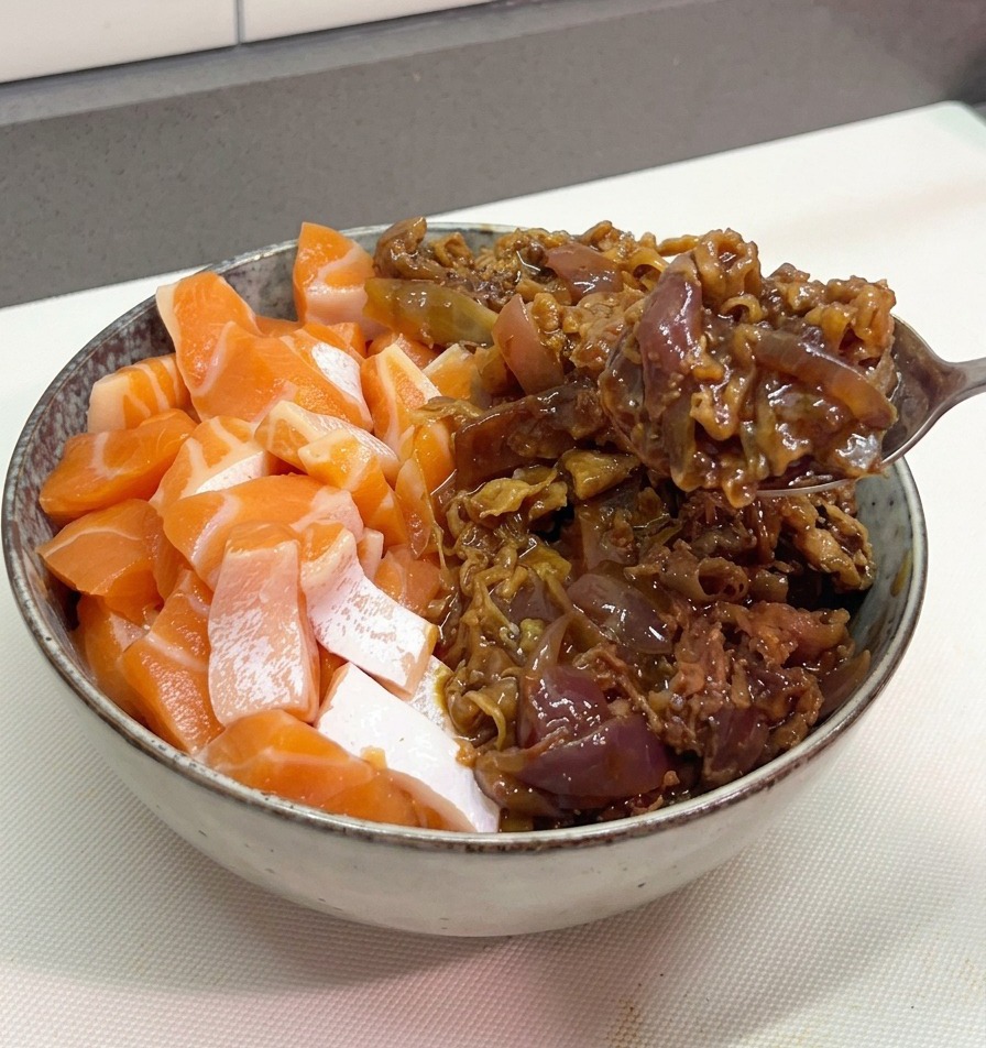 Une cuillère métallique déposant une généreuse portion de bœuf sauté en sauce et doignons violets dans un bol contenant déjà des morceaux de saumon frais.