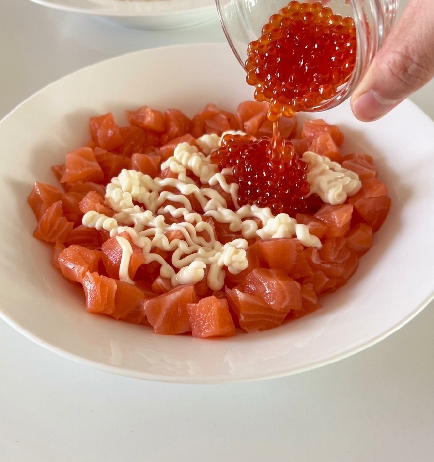 Dés de saumon frais dans un bol blanc, agrémentés dœufs de poisson rouge vif et de mayonnaise crémeuse.
