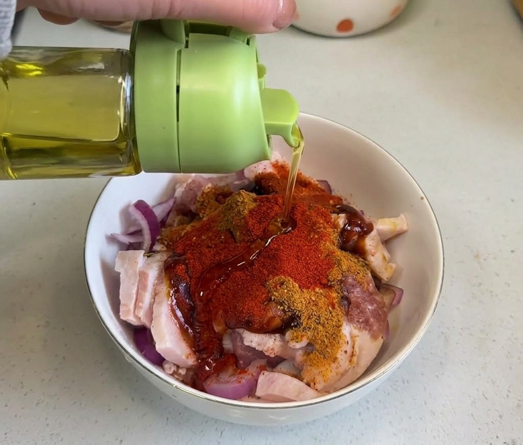 De lhuile de cuisson limpide versée depuis une bouteille verte sur le mélange de porc épicé.