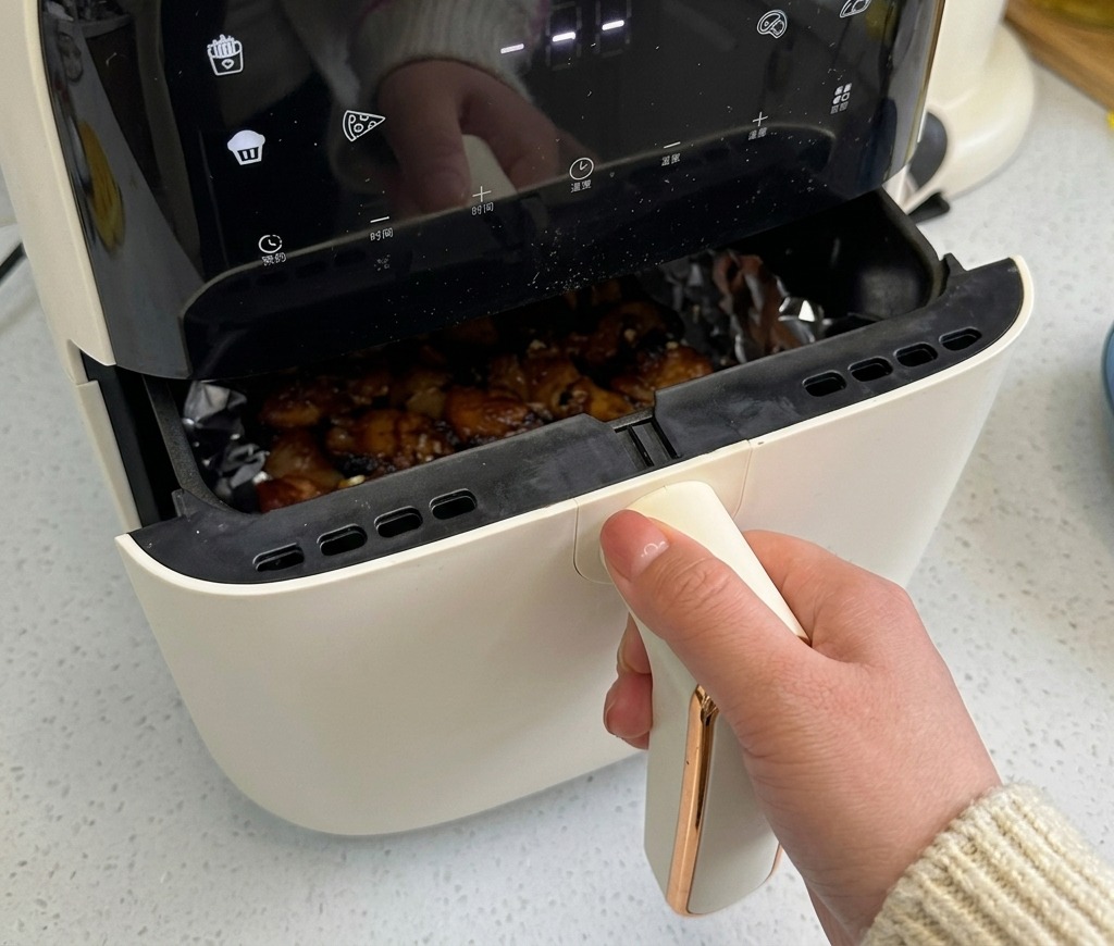 Le panier du air fryer entrouvert, montrant la poitrine de porc qui commence à dorer et à grésiller.