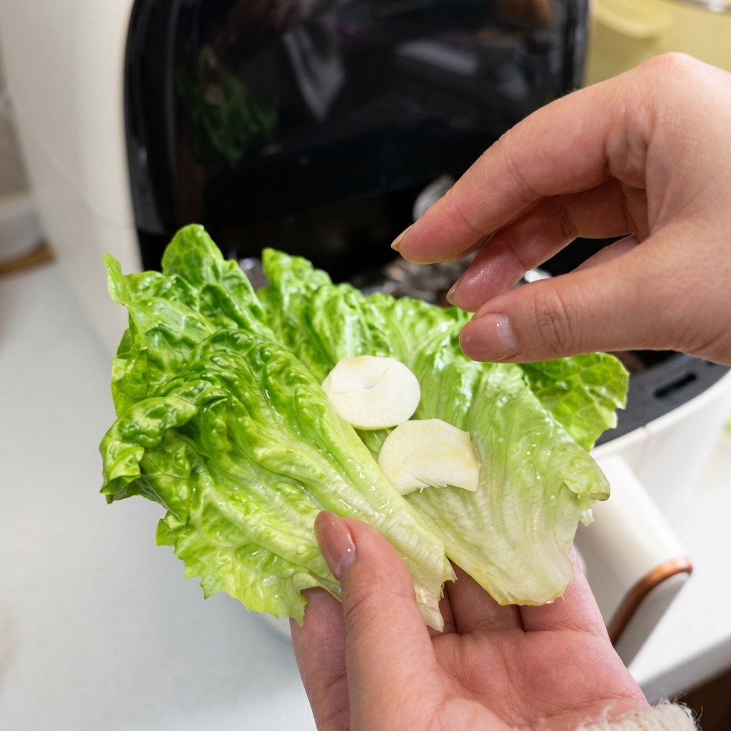 Gros plan dune main tenant une feuille de salade verte garnie de fines rondelles dail blanc.