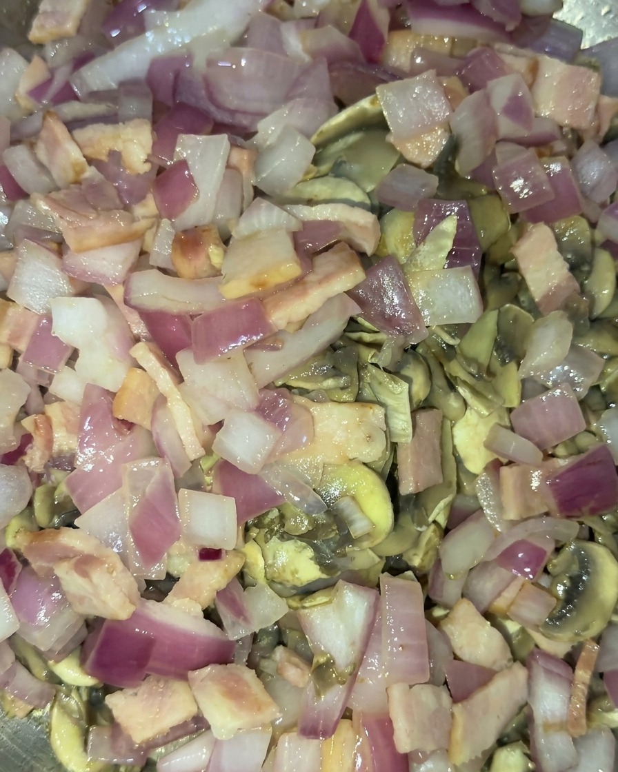 Mélange combiné de champignons sautés dorés, doignons rouges translucides et de morceaux de lardons cuits saisis ensemble.