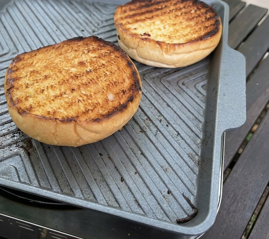 Une cuillère en argent étalant une épaisse sauce rose onctueuse sur la surface dorée dun pain brioché toasté.