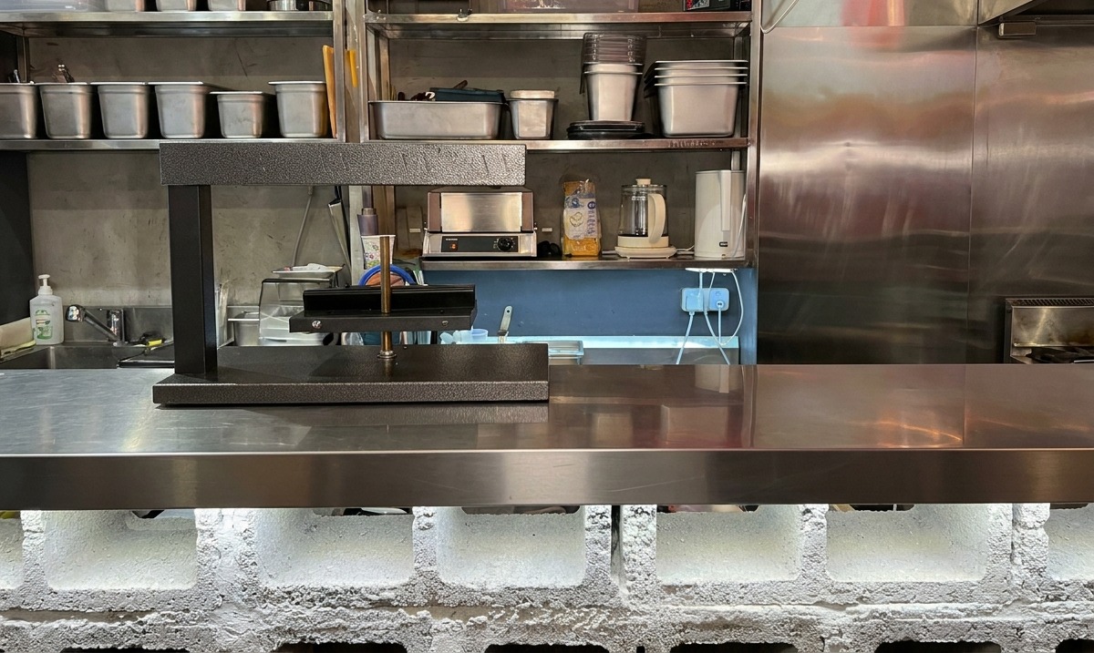 Un appareil à raclette électrique professionnel noir installé sur un plan de travail en inox.