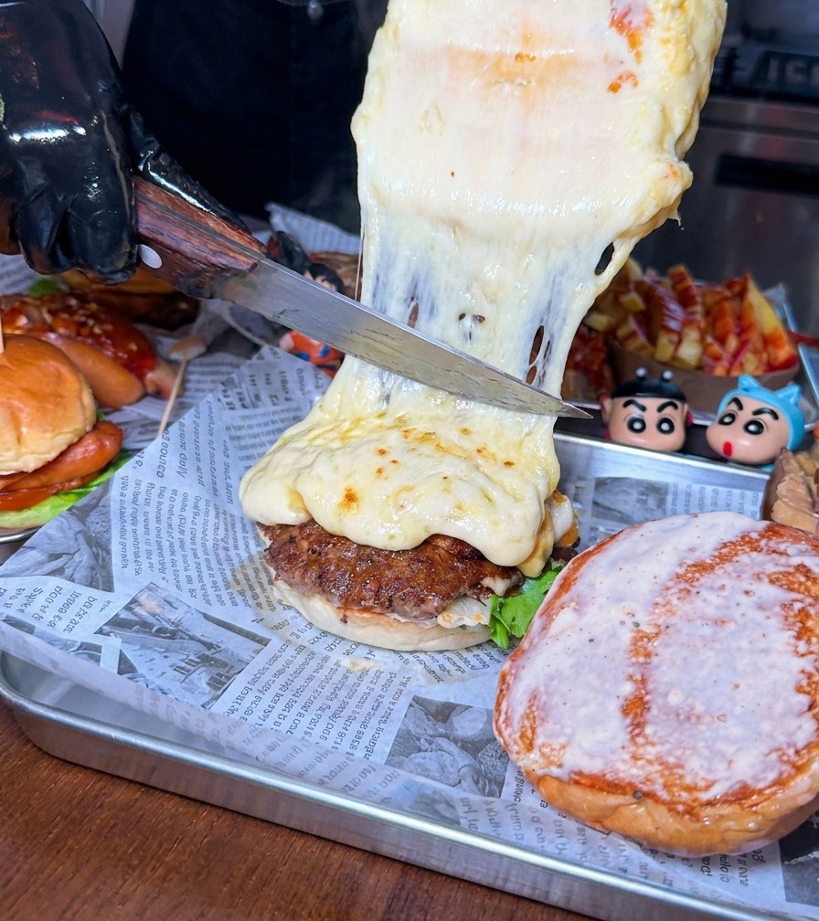 Un grand couteau raclant une épaisse couche de fromage fondu sur un steak de bœuf.