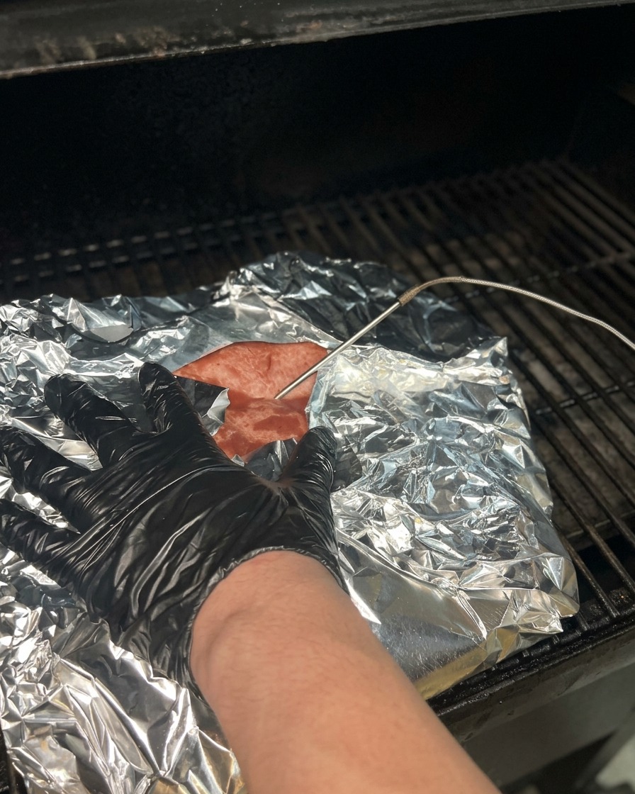 Une sonde de température insérée à travers le papier daluminium dans un brisket cuit pour vérifier sa tendreté.