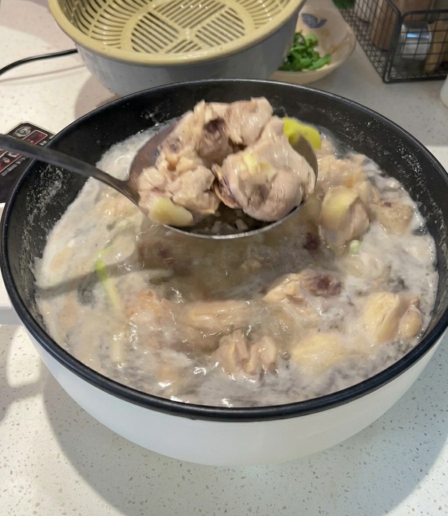 Une louche en métal sortant des morceaux de poulet blanchis et opaques dune casserole deau bouillante et écumeuse.