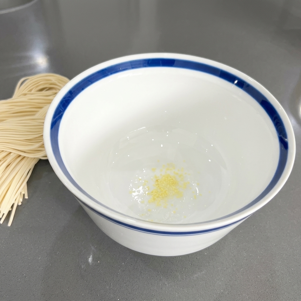 Petits morceaux dail émincé aux reflets jaunâtres reposant au fond dun bol en céramique blanche.