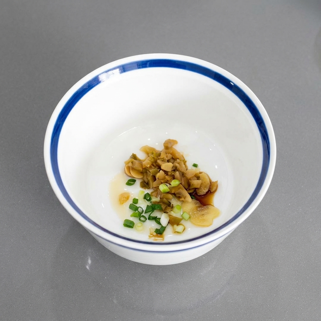 Oignons verts émincés mélangés aux légumes saumurés et à lail au fond dun bol en céramique blanche.