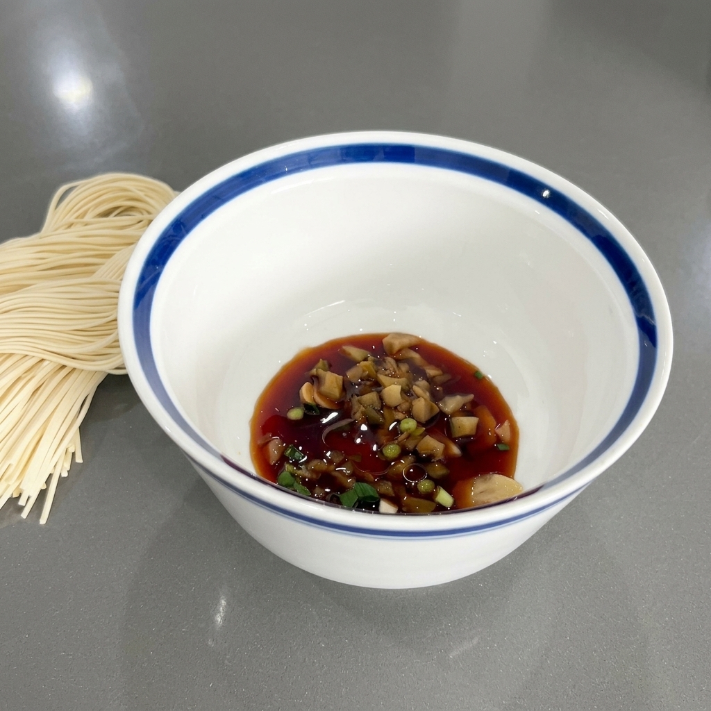 Le bol contenant la sauce soja, les oignons verts et les aromates, affichant un léger éclat brillant dû à lajout de lhuile de sésame.