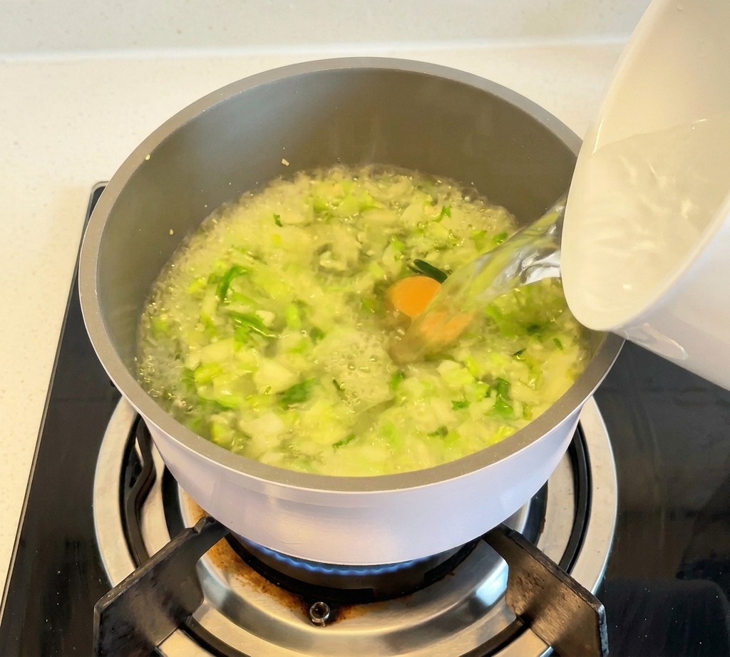De leau bouillante versée dun récipient blanc dans une marmite remplie de légumes et de bouillon clair.