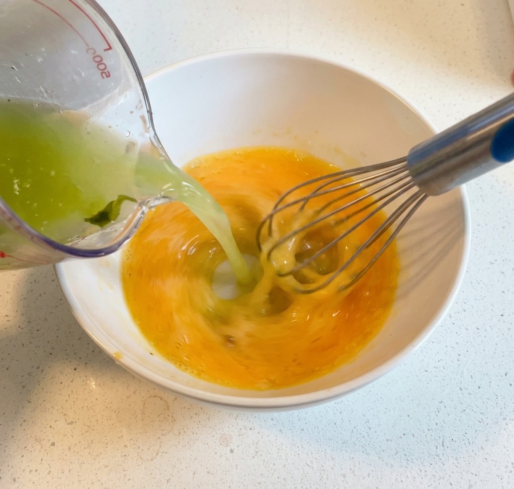 Du bouillon chaud versé dune louche dans un bol dœufs battus au citron, tout en mélangeant énergiquement au fouet.