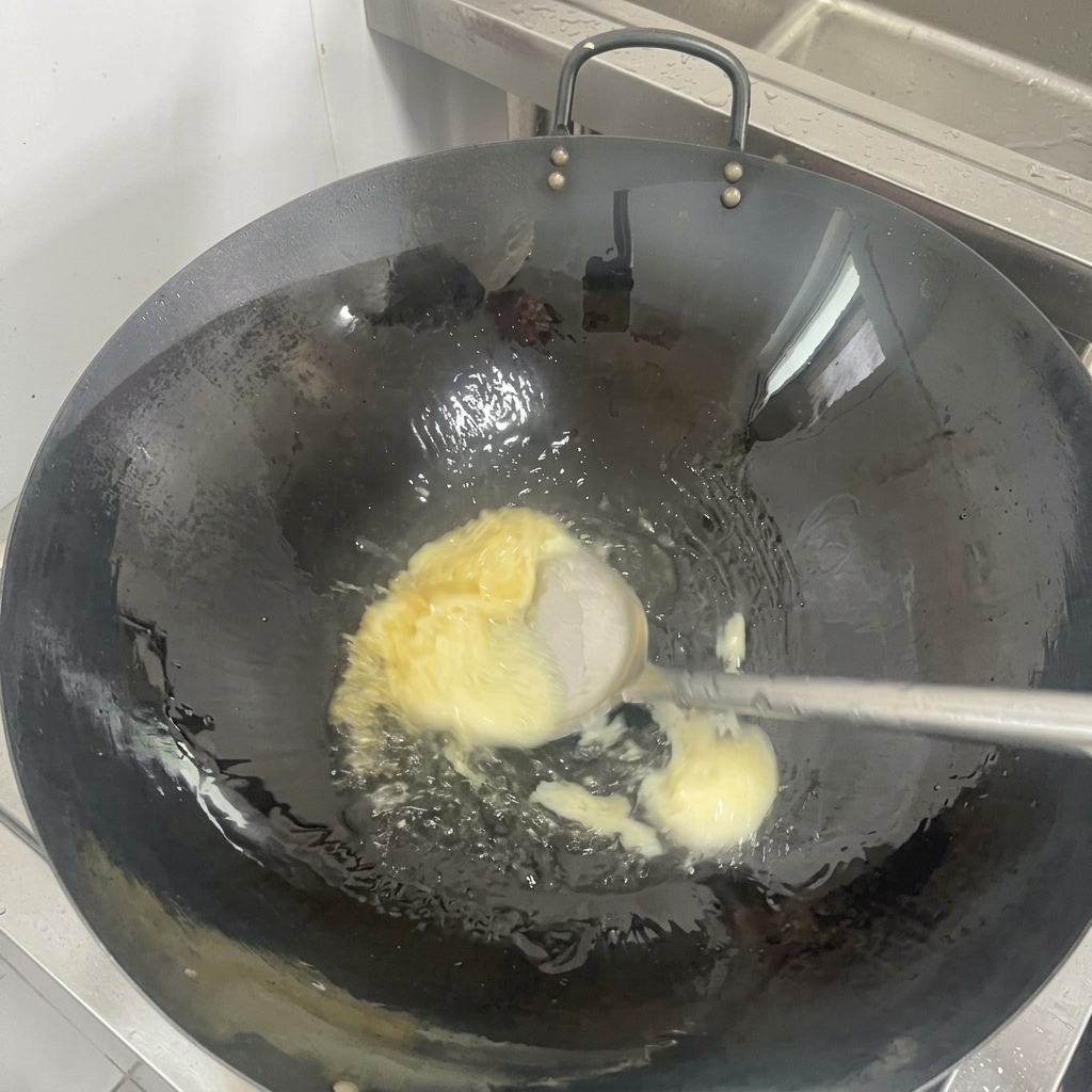 Un morceau de saindoux blanc fondant en une huile claire au fond dun wok noir culotté.