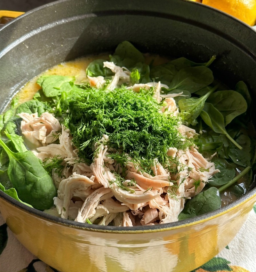 Une marmite de soupe garnie de poulet blanc effiloché et dun grand dôme daneth frais finement haché.