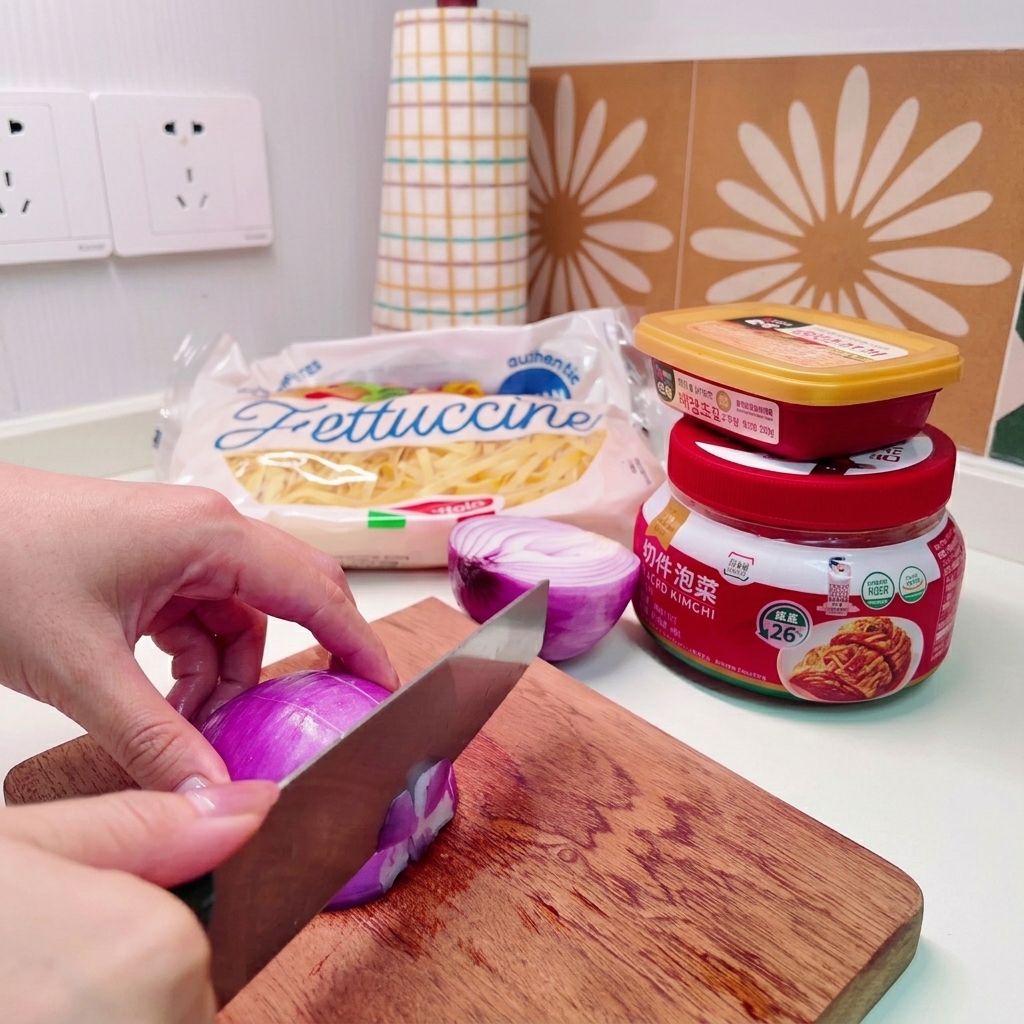 Gros plan sur des mains utilisant un couteau pour couper un oignon rouge en petits dés sur une planche en bois.