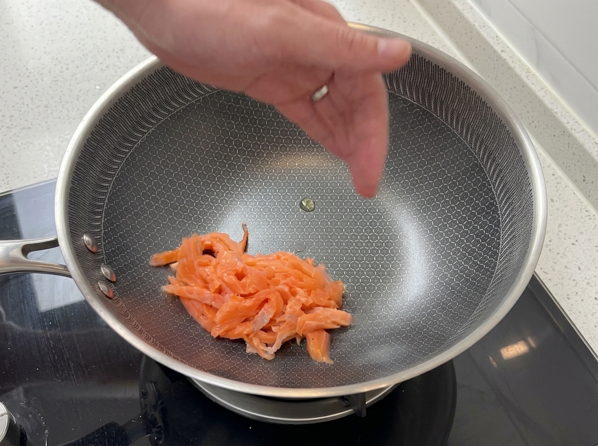 Des tranches de saumon fumé rose saisies dans une poêle en acier inoxydable.