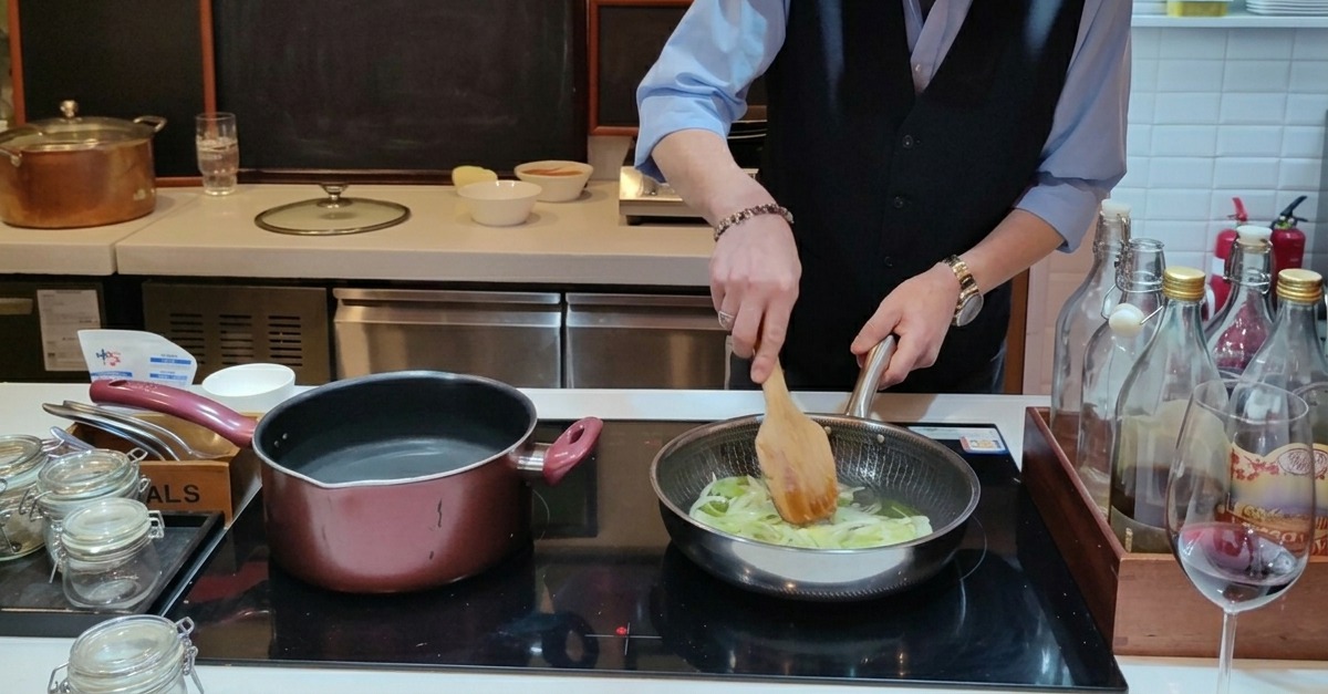 Fines lamelles doignons qui dorent dans une poêle avec de lhuile dolive, remuées avec une spatule en bois.