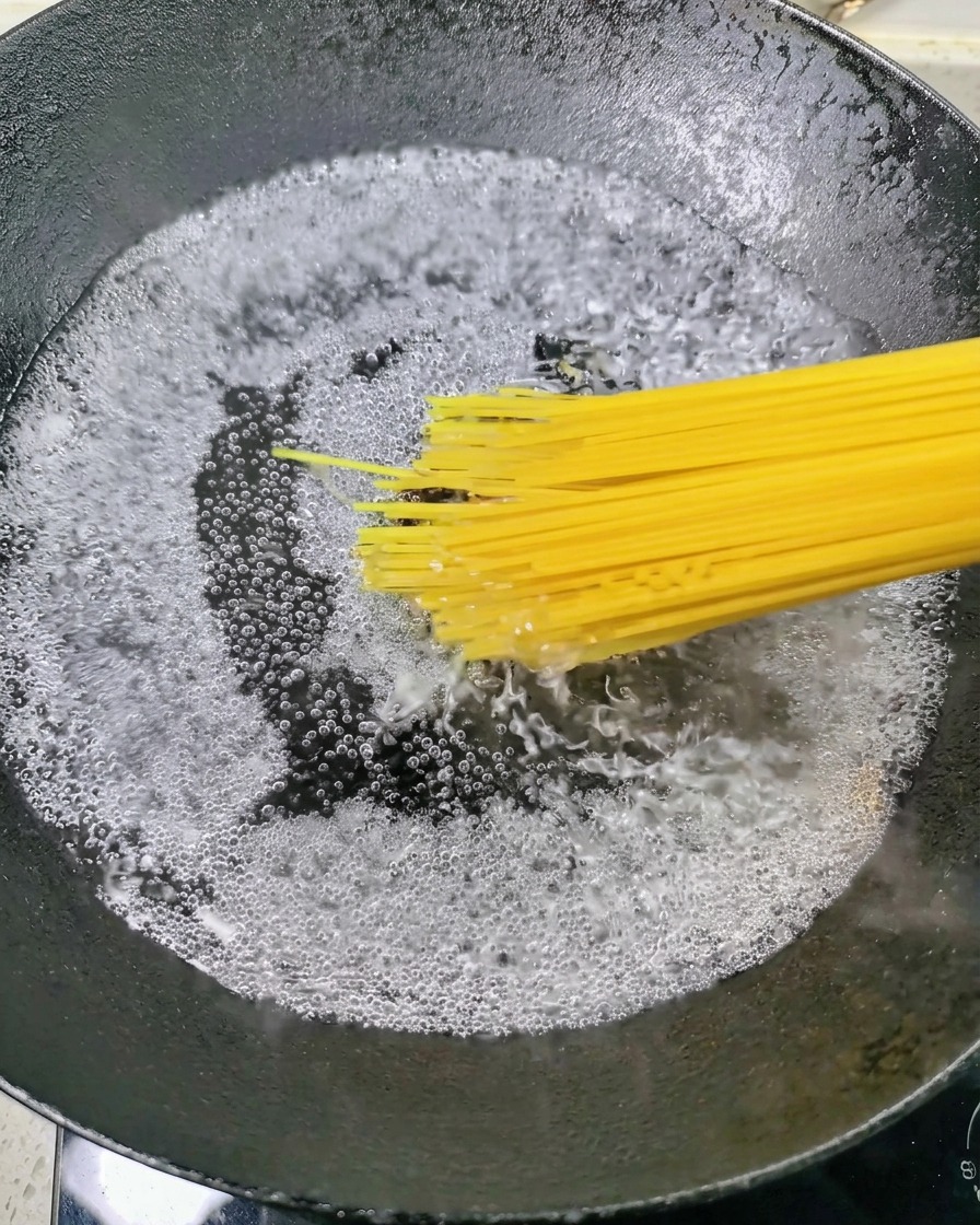 Des spaghettis secs plongés dans une casserole deau bouillante.