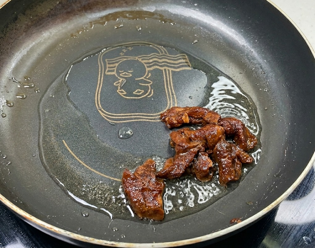 Lamelles de porc marinées sautant dans une poêle huilée, affichant une couleur brune brillante en fin de cuisson.