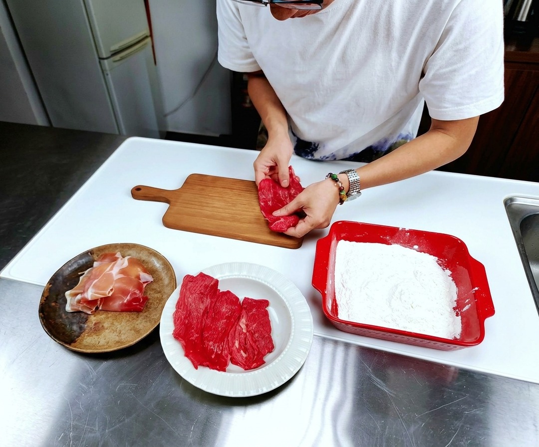 Fines tranches de veau cru étalées à plat sur une planche à découper en bois.