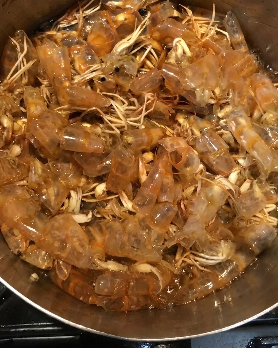 Carapaces de crevettes mijotant dans un mélange de sauce sombre à lintérieur dune casserole.