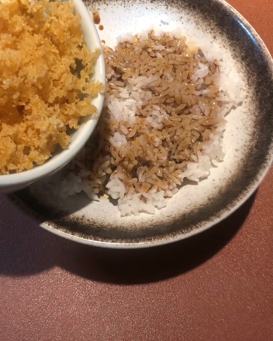 Miettes de pâte frites dorées saupoudrées sur un bol de riz et de sauce.