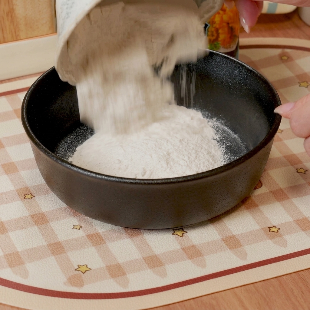 Un fouet mélangeant la farine à tempura et leau dans un bol pour obtenir une pâte lisse.
