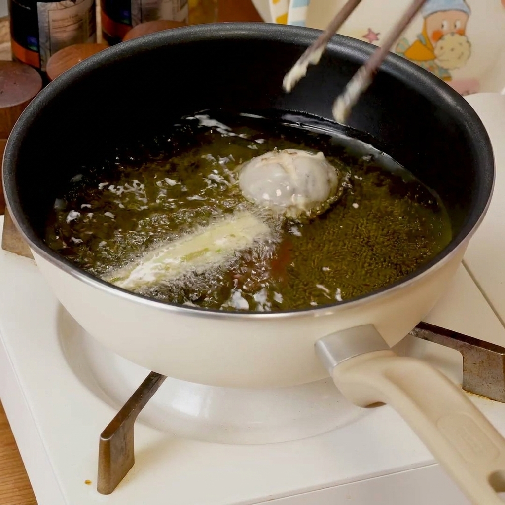 Pièces de tempura frisant dans une poêle dhuile chaude, devenant dorées.