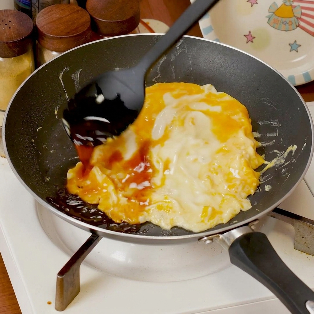 Sauce savoureuse versée sur les œufs brouillés cuisant dans une poêle.