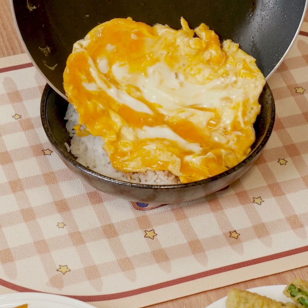 Œufs brouillés à la sauce versés sur un bol de riz blanc.