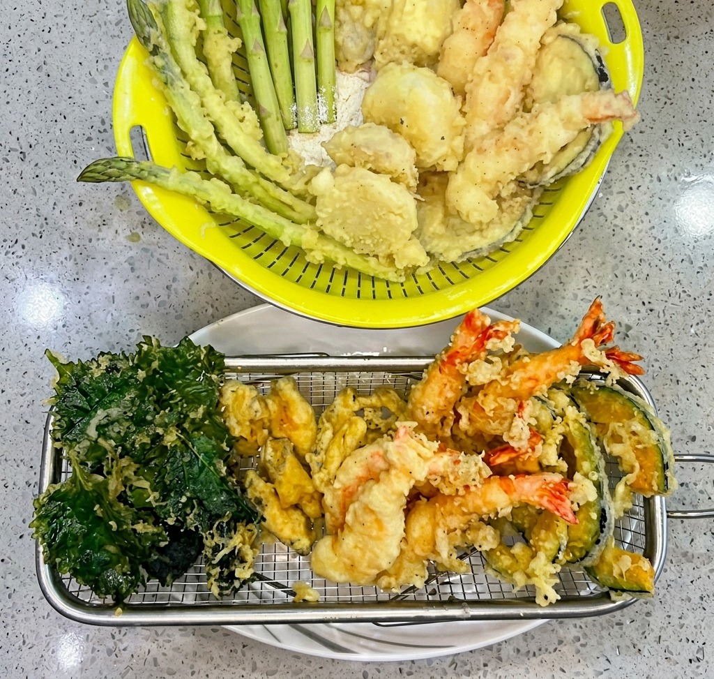 Crevettes enrobées de pâte à tempura plongées dans de lhuile chaude dans un panier à friture.