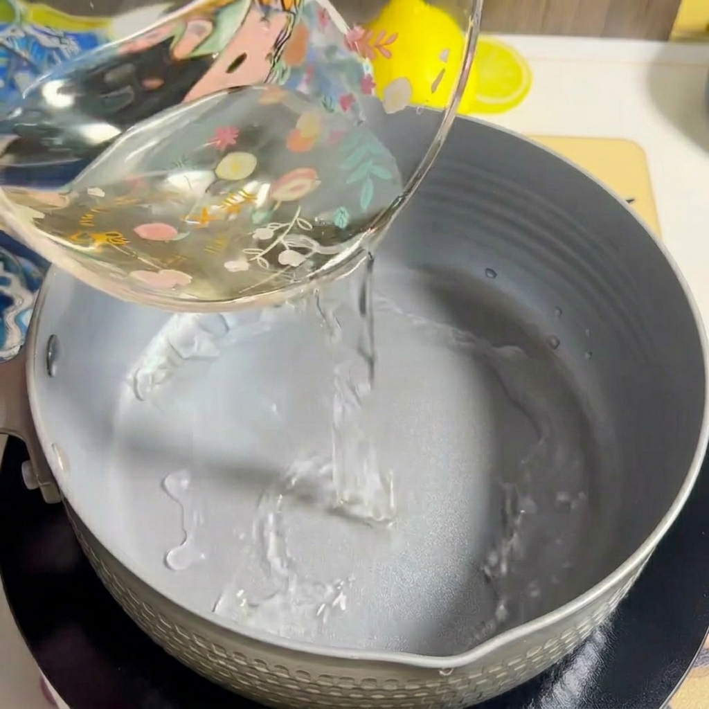 De leau est versée dans une casserole vide sur une plaque de cuisson.