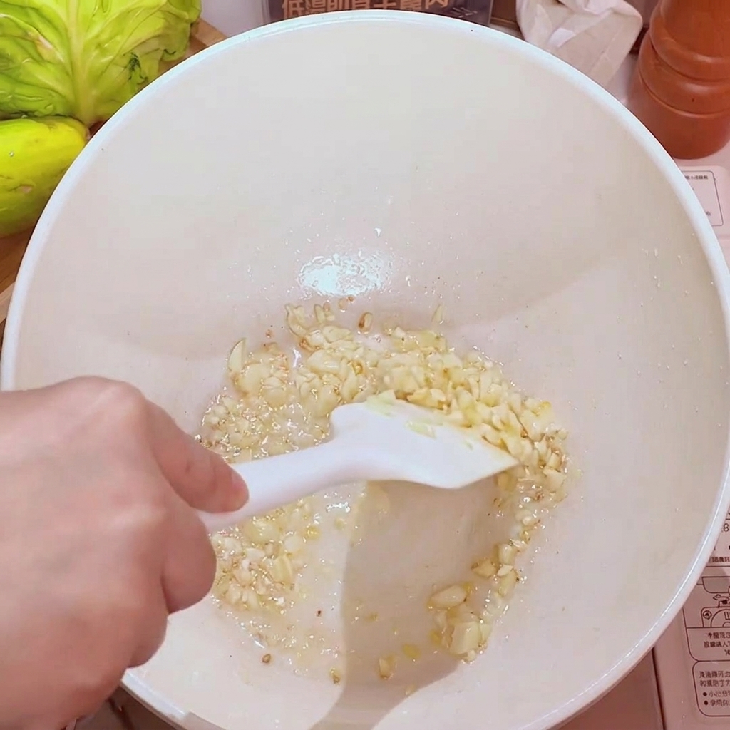 Ail haché grésillant dans une poêle avec de lhuile, devenant doré et aromatique.