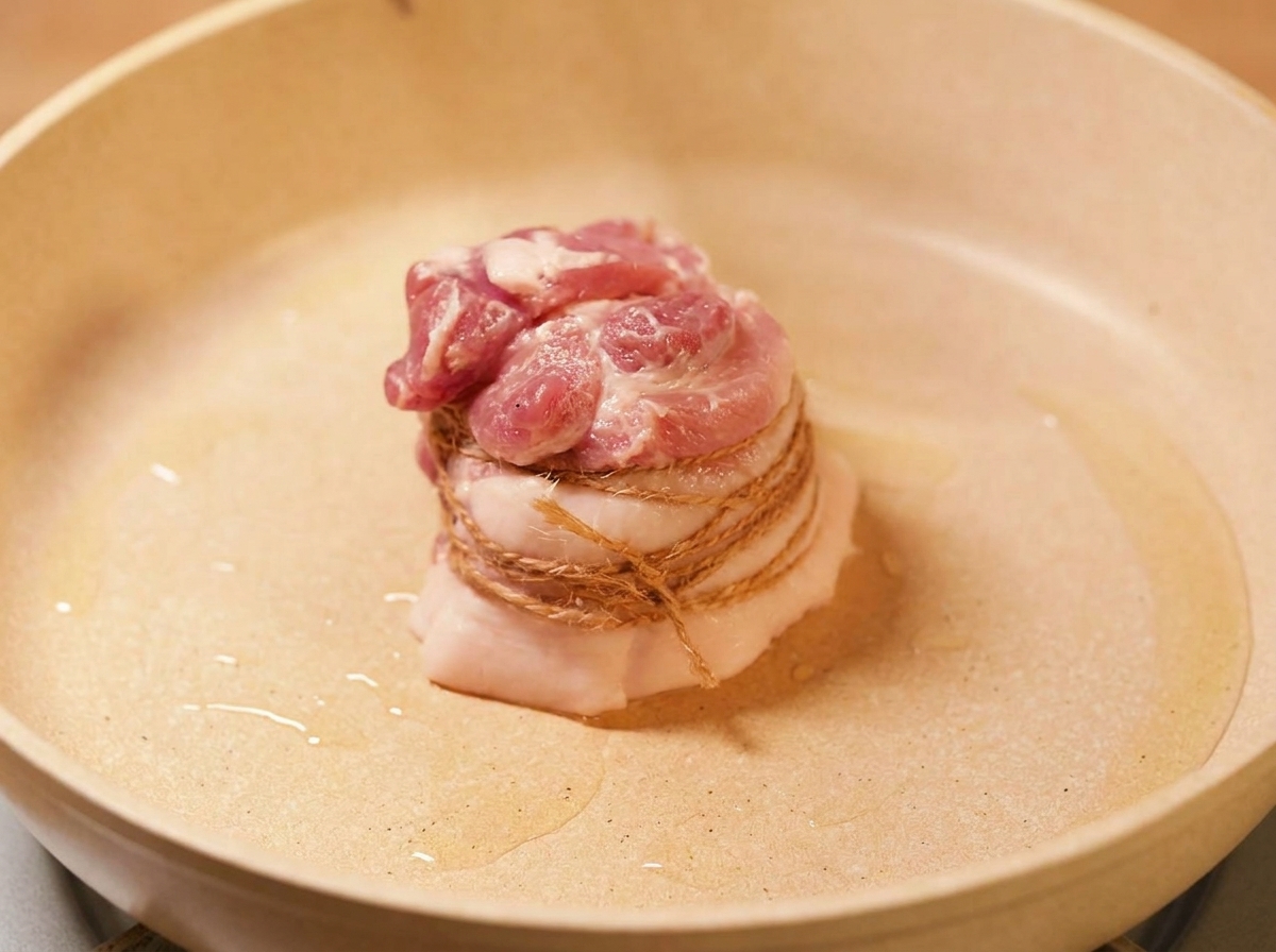 La poitrine de porc ficelée saisie dans une poêle avec de lhuile chaude jusquà coloration dorée.
