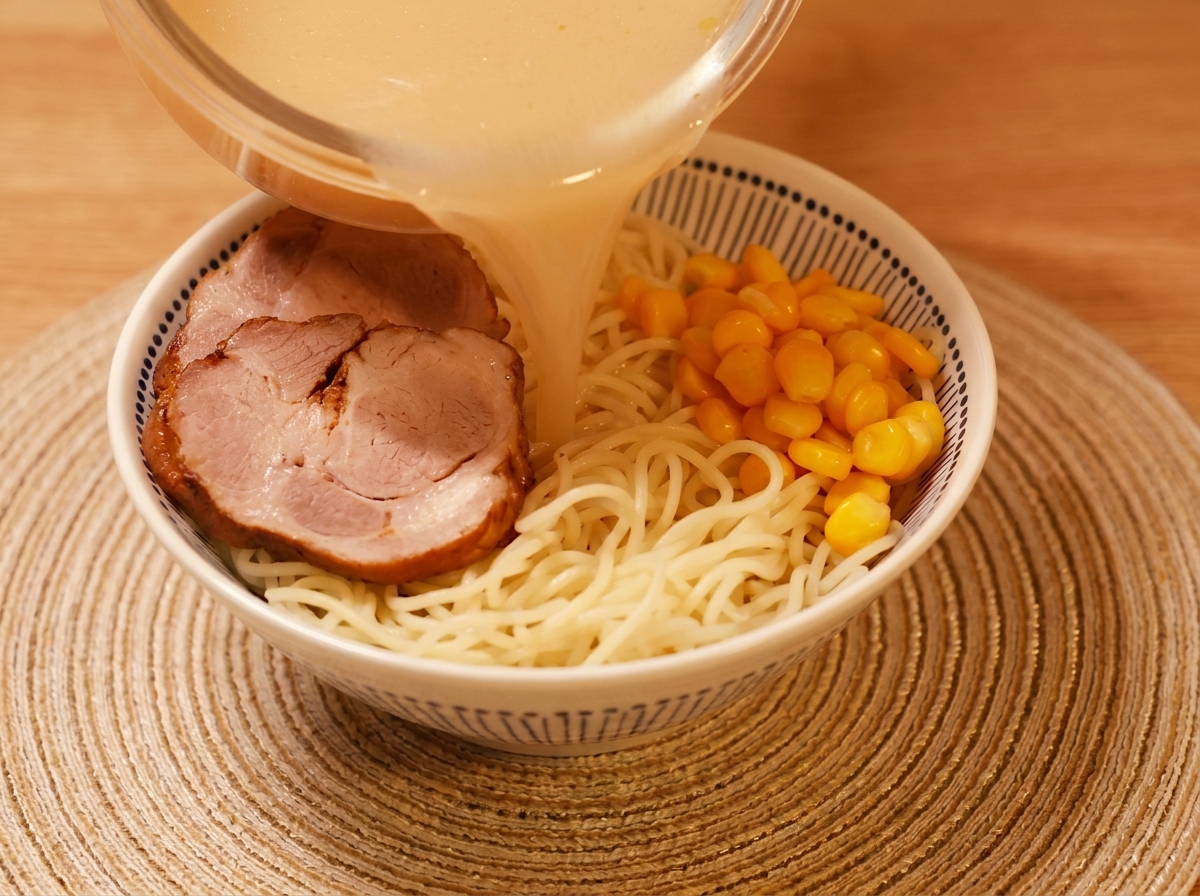 Vue de dessus dun bol de ramen rempli de bouillon miso crémeux, agrémenté de porc, nouilles et maïs.