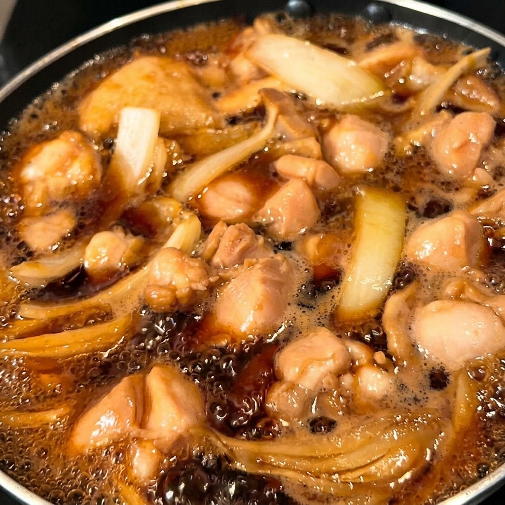 La moitié du mélange dœufs versée dans la poêle sur le poulet et les oignons.