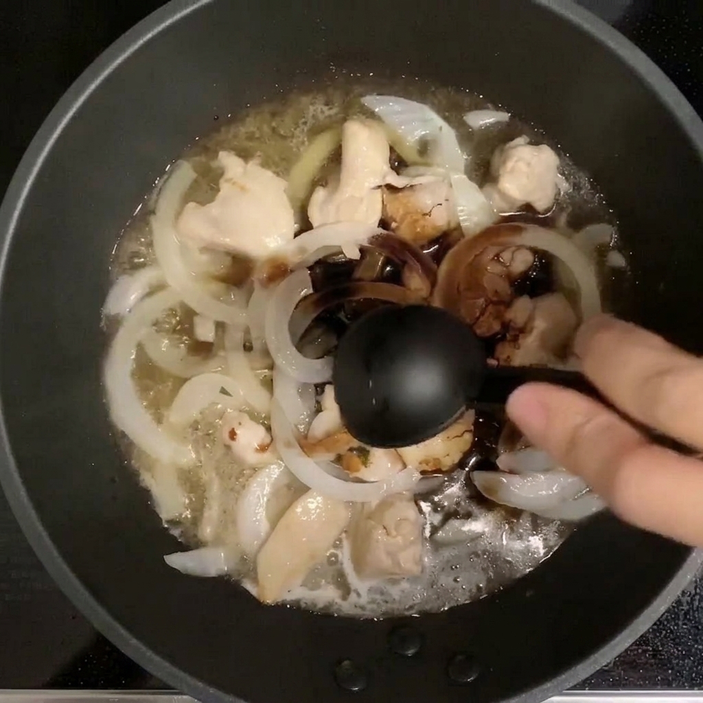 Cuillère versant les assaisonnements dans la poêle contenant le poulet et les oignons.