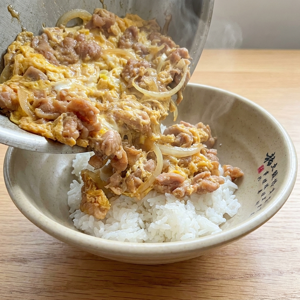 Le plat fini de Tanindon servi dans un bol, avec porc, oignons et œufs onctueux sur du riz blanc.
