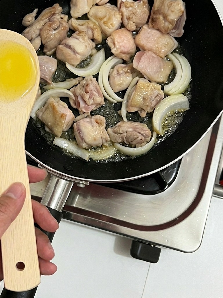 Des lamelles doignon incorporées dans la poêle avec les morceaux de poulet.