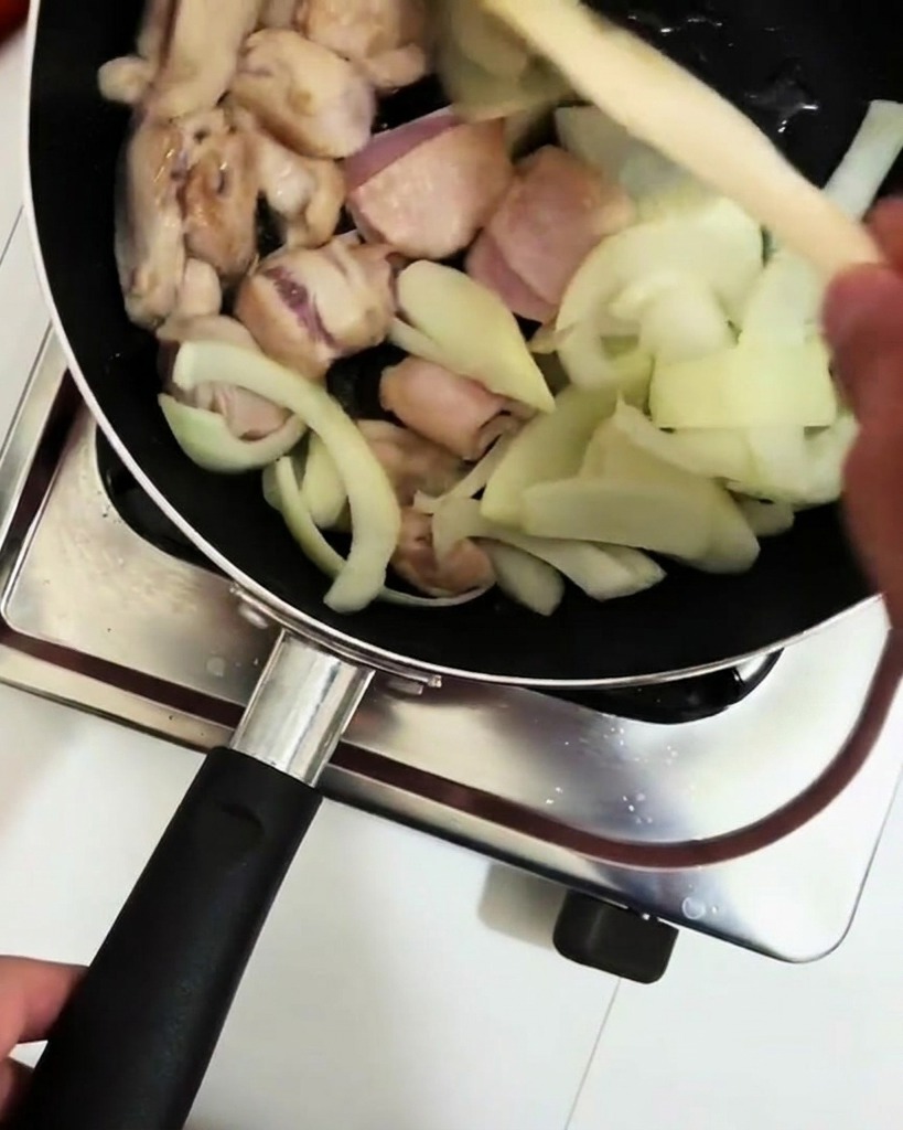 Du vin de cuisine versé dune louche dans la poêle avec le poulet et les oignons.