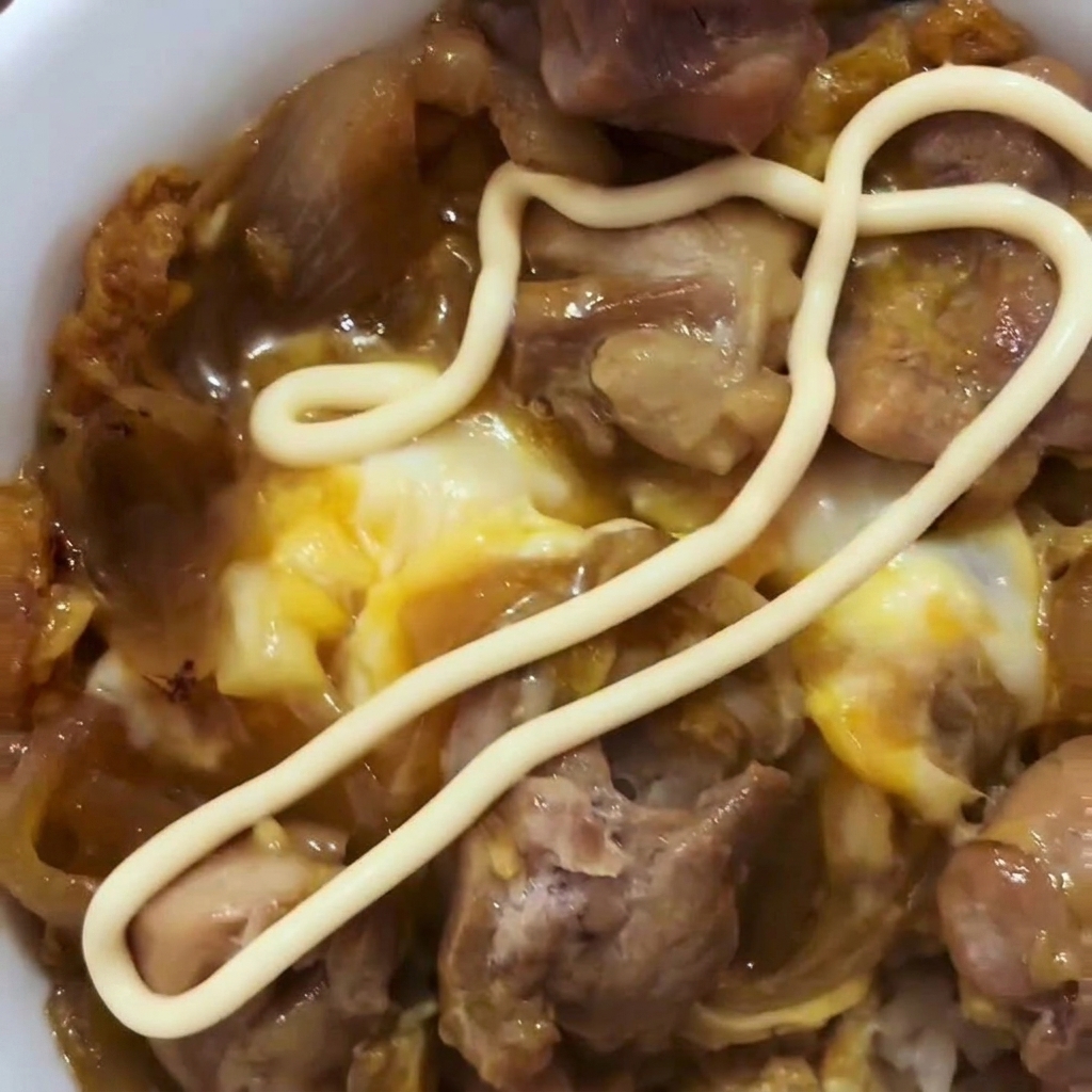 Des œufs battus versés sur le poulet et les oignons cuits dans une poêle.