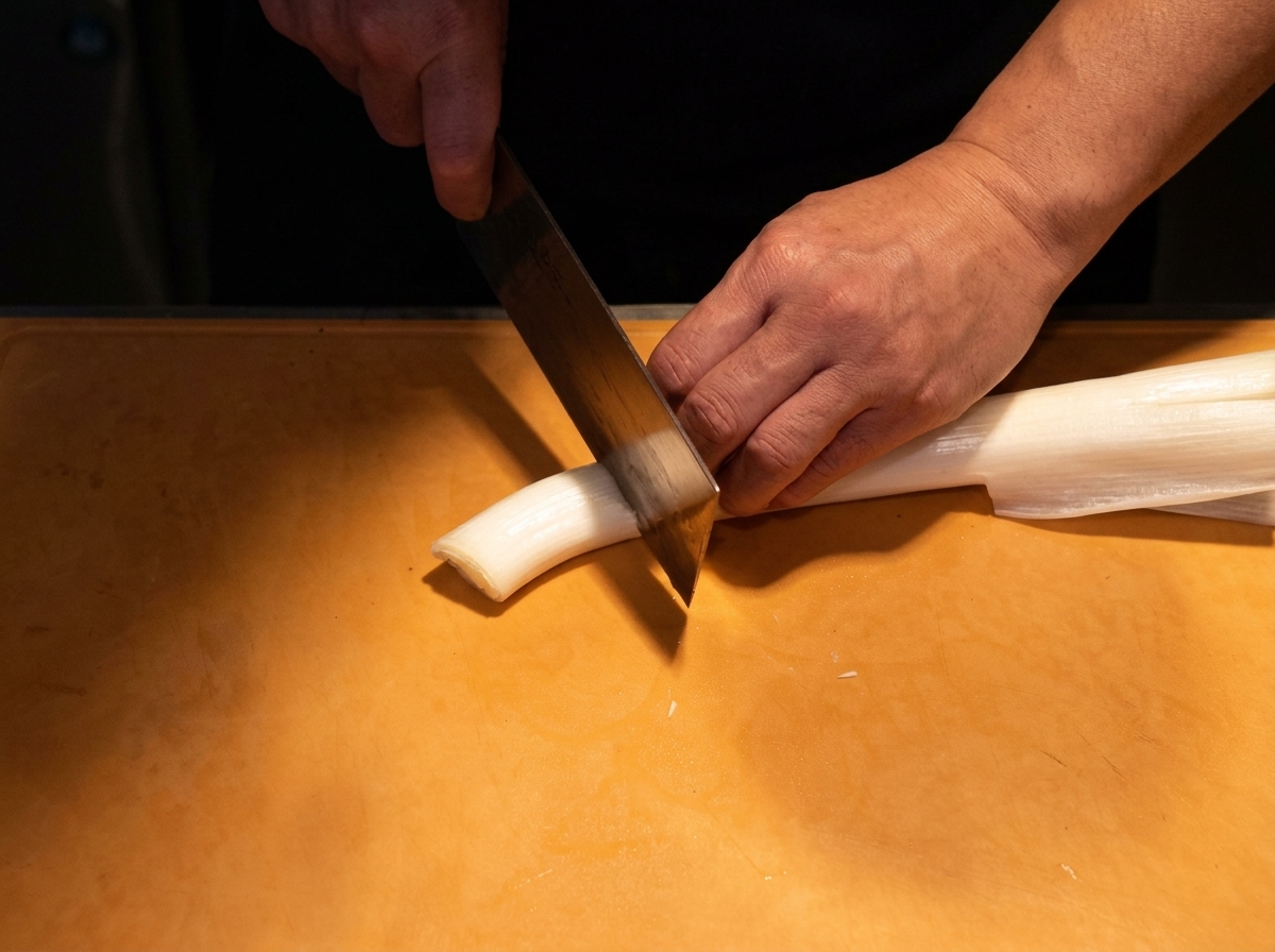 Le blanc dun oignon long japonais coupé en fines tranches en diagonale sur une planche à découper.