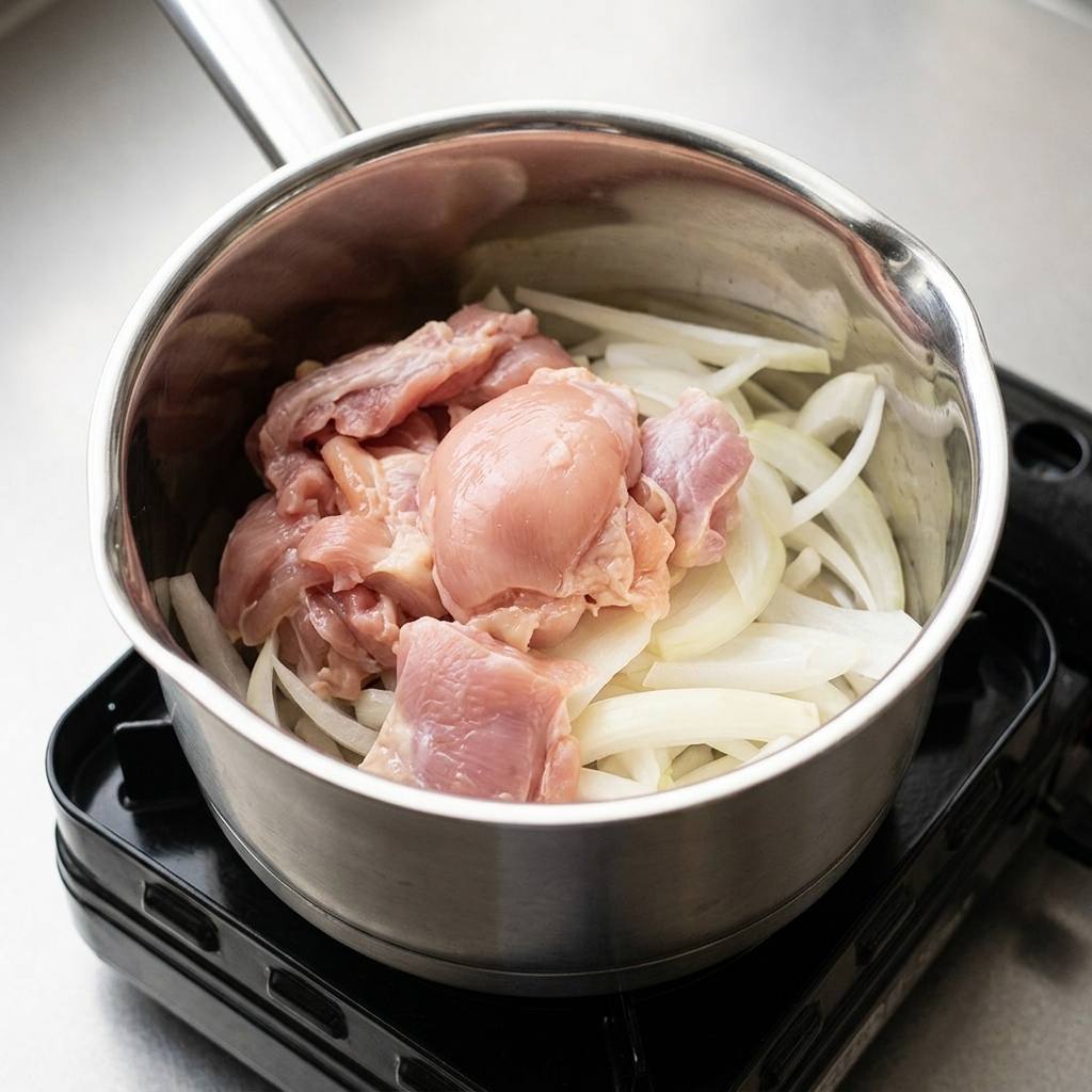Oignons et morceaux de poulet dans une casserole, agrémentés dassaisonnements liquides.