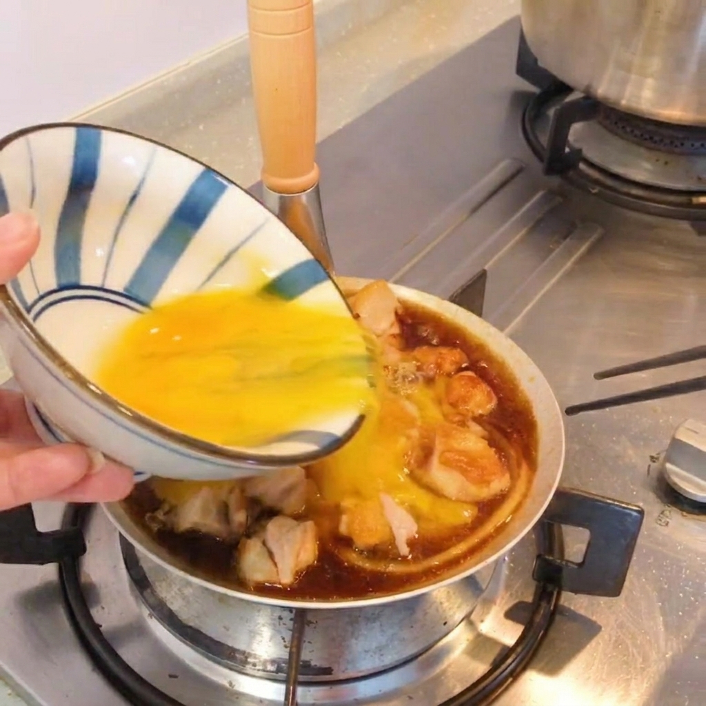Un plat façon Oyakodon terminé dans une poêle, garni doignons verts frais.