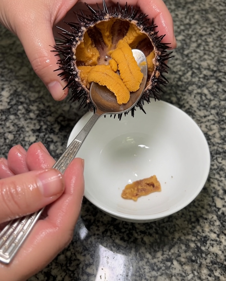 Une cuillère en métal soulève les segments duni orange pour les placer dans un bol en céramique.