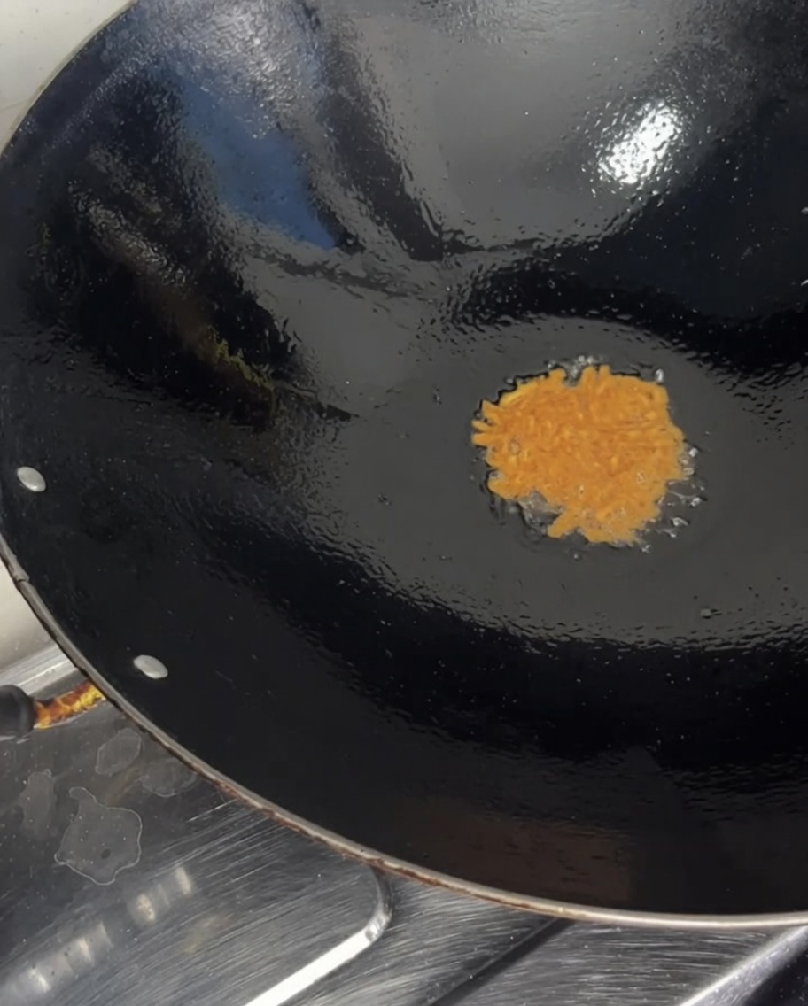 Les segments duni orange sont versés dans un wok chaud.