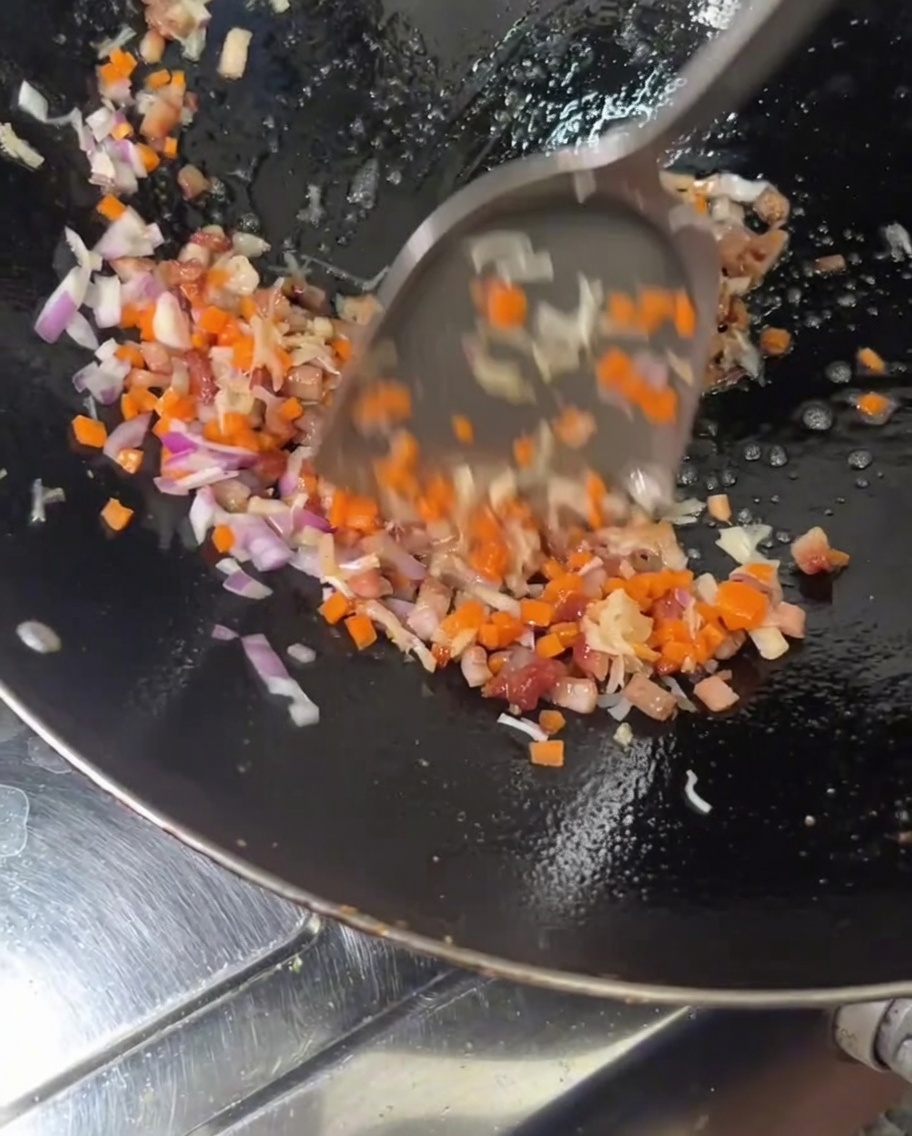 Les carottes et loignon rouge sont ajoutés aux viandes dans le wok.