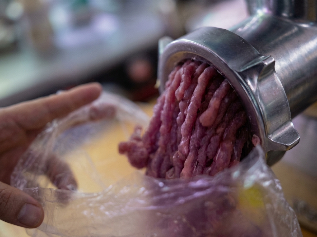 Viande hachée sortant dun hachoir mécanique dans un sac en plastique.