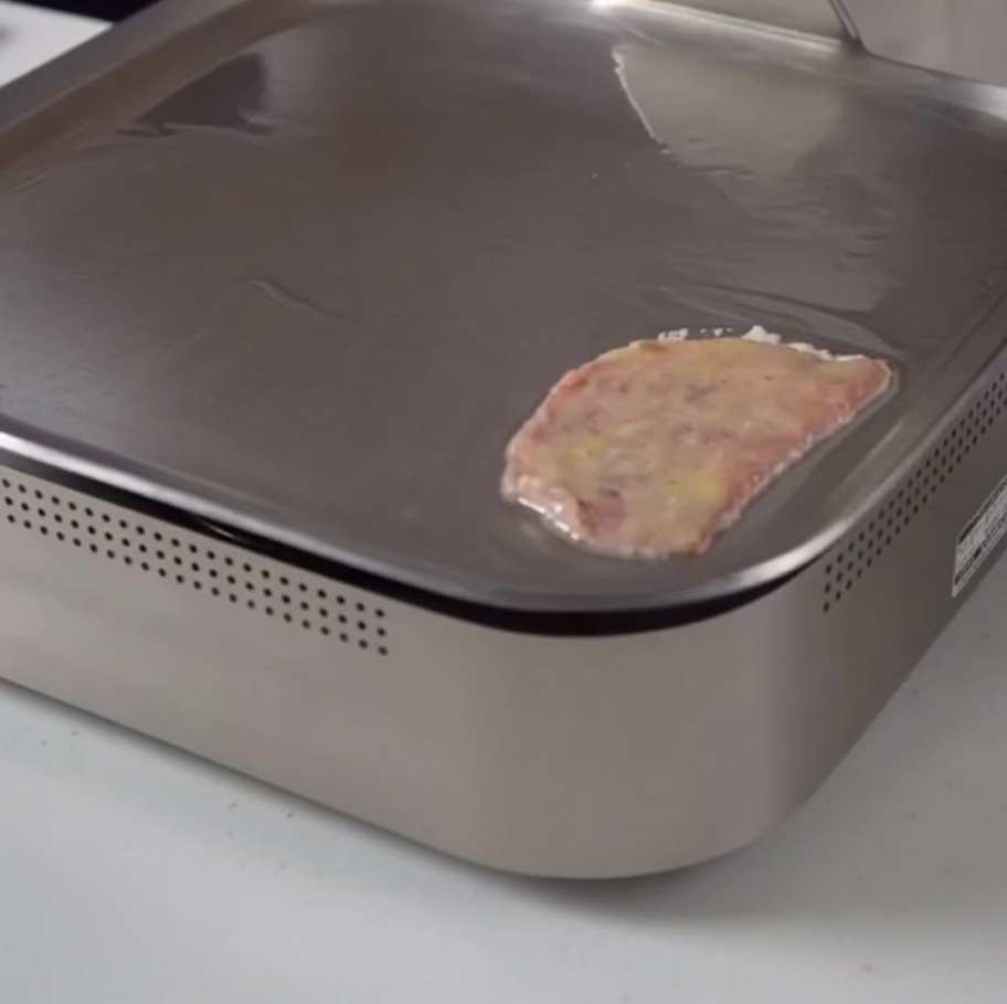 Une tranche de bœuf enrobée dœuf en train de cuire doucement sur une plaque de cuisson plate.